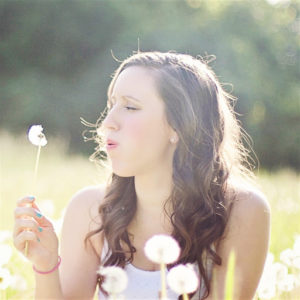 Woman blowing on a dandelion creating an auditory trigger